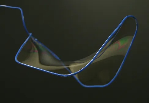 A soap film stretched across a wire frame, forming a smooth minimal surface
